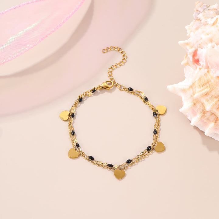 Bracelet Candy, perles noires et blanches et cœurs dorés suspendus